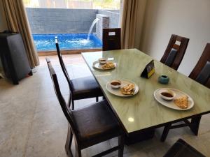 a dining room table with plates of food on it at Twilight Stays ll 2 Bed Villa ll Swimming Pool ll AC ll BBQ in Lonavala +3 photos