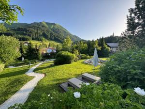 a garden with a bench and an umbrella in the grass at Hotel Singer – Relais & Châteaux in Berwang