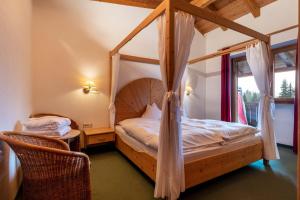 a bedroom with a canopy bed and a chair at Sabina Dolomites Lärche in Alpe di Siusi +22 photos