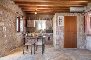 a kitchen with a table and chairs in a stone wall at Villa Lazar in Lefkada