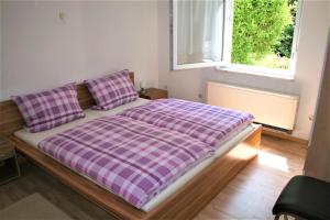 a bed with a purple plaid blanket and a window at Haus am Waldrand in Triberg