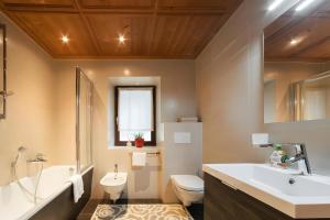 a bathroom with a sink and a toilet and a tub at Ciasa Ilda - Charming House 120 M2 in La Valle