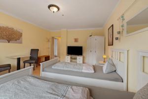 a bedroom with two beds and a desk and a tv at Ferienwohnungen Golsong in Thaleischweiler-Fröschen