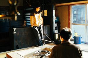 Ein Mann steht vor einem Spiegel in einem Zimmer in der Unterkunft MEKIKI古民家 yorimichi in Yamanashi + 7 Fotos