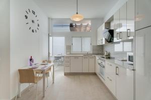 a kitchen with white cabinets and a table and a clock at Serenity in Arona