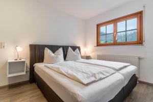 a bedroom with a large bed with white sheets and a window at Haus Sum in Oberwolfach