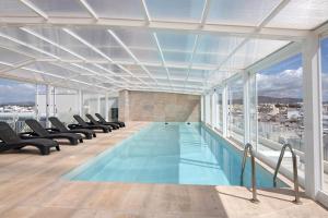 a swimming pool in a building with chairs at Mare Nostrum in Olhão