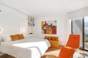 a white bedroom with a bed and orange chairs at Mare Nostrum in Olhão +24 photos