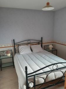 a bedroom with a bed with white sheets and two tables at la fontaine bénite in Seyssel
