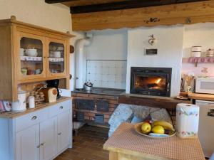 a kitchen with a fireplace and a table with a bowl of fruit at Baita Nido tra i Monti in Daone