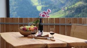 a wooden table with a bowl of fruit and wine glasses at Bergchalet Prantach in San Martino