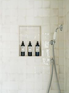three bottles in a niche in a white tiled shower at The Queen's Head in Broad Chalke