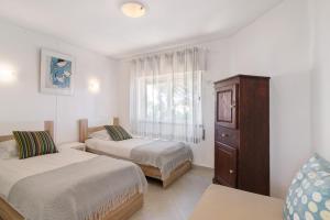 a bedroom with two beds and a dresser and a window at Townhouse Ramas in Vale do Lobo
