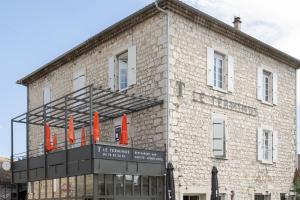 a brick building with orange umbrellas in front of it at Syrah in Ruoms +9 photos