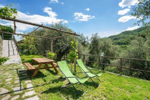 a couple of chairs and a picnic table in the grass at La casa di Bosco in Casanova Lerrore