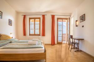 a bedroom with a bed and a desk and two windows at Residence Lena App 3 with Balcony in Tenno