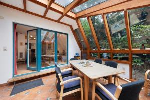 a conservatory with a wooden table and chairs at Ferienhaus am Brandorffsee in Wiefelstede
