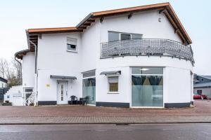 a white house with a balcony on top of it at Saarglück - W4 in Beckingen