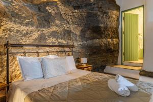a bedroom with a bed with a rock wall at Traditional Olive Guesthouse in Fállika