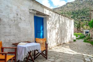 a table and chairs in front of a building with a blue door at Traditional Olive Guesthouse in Fállika
