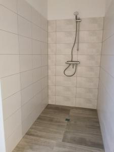 a bathroom with a shower with white tiled walls at Ferienhäuser Ebbe und Flut in Schülp +18 photos