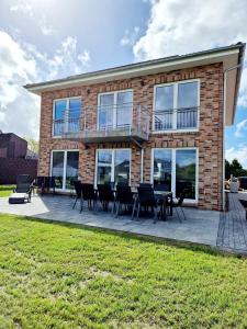 a brick house with a deck and tables and chairs at Ferienhäuser Ebbe und Flut in Schülp