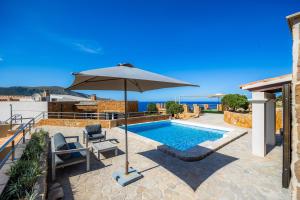 a swimming pool with an umbrella and a chair and a table and a swimming pool at Can Eolo in Capdepera