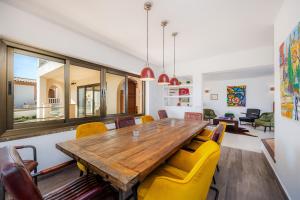 a dining room with a wooden table and yellow chairs at Can Eolo in Capdepera