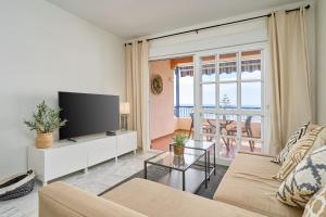 a living room with a couch and a tv at Jardines del Mar in Torrox
