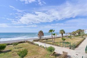 a walkway to the beach with palm trees and the ocean at Jardines del Mar in Torrox