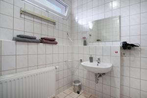 a white tiled bathroom with a sink and a mirror at Forst Entdecken in Forst +15 photos