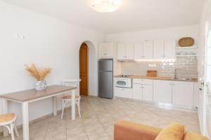 a kitchen with white cabinets and a table and chairs at Anemologio 101 Tinos in Agios Ioannis