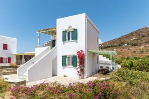 a white house with green shutters and flowers at Anemologio 101 Tinos in Agios Ioannis +13 photos