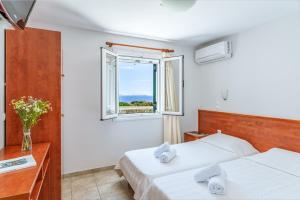 a hotel room with two beds and a window at Anemologio 101 Tinos in Agios Ioannis
