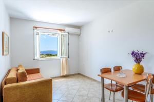 a living room with a couch and a table and a window at Anemologio 101 Tinos in Agios Ioannis