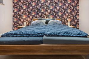 a bedroom with a blue bed with a floral wallpaper at Ferienwohnung Silberborth mit Sauna in Seesen