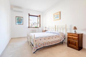 a white bedroom with a bed and a wooden dresser at Stella Vacanze in Otranto