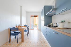 a kitchen with a table and blue cabinets and blue chairs at Stella Vacanze in Otranto