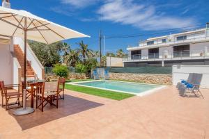 a patio with an umbrella and a swimming pool at Villa Payu in Ciutadella