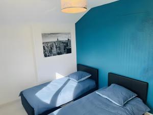 a bedroom with two beds and a blue wall at Gîte Le Flot in Saint-Florentin +9 photos