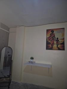 a white wall with a table and a picture on it at Nimaai Apartment in Narok