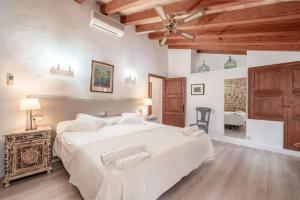 a bedroom with a large white bed and a wooden ceiling at Villa Agnes in Pollença +26 photos