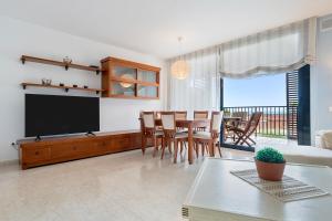a living room with a television and a table and chairs at Ática Blue Sea in Cubelles