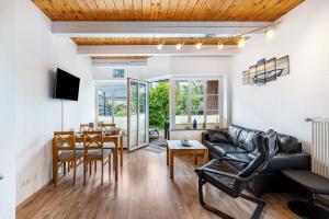 a living room with a black leather couch and a table at Kleiner Leuchtturm - Steuerbord in Fehmarn