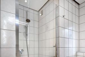 a bathroom with a shower with white tiled walls at Gelis Ferienwohnung in Ihringen +14 photos