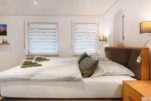 a bedroom with a large white bed with two windows at Gelis Ferienwohnung in Ihringen