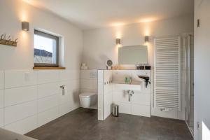 a white bathroom with a toilet and a window at Design Ferienhaus 195qm in Breitbrunn am Chiemsee +22 photos