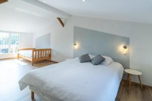 a white bedroom with a large bed with two pillows at Le Séchoir in Saint-Amand-de-Coly +17 photos