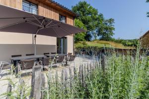 a patio with a table and chairs and an umbrella at Le Séchoir in Saint-Amand-de-Coly