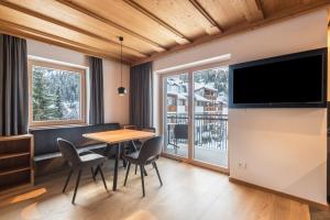 a dining room with a table and chairs and a television at La Grambla App Mont Seuc in Santa Cristina Gherdëina